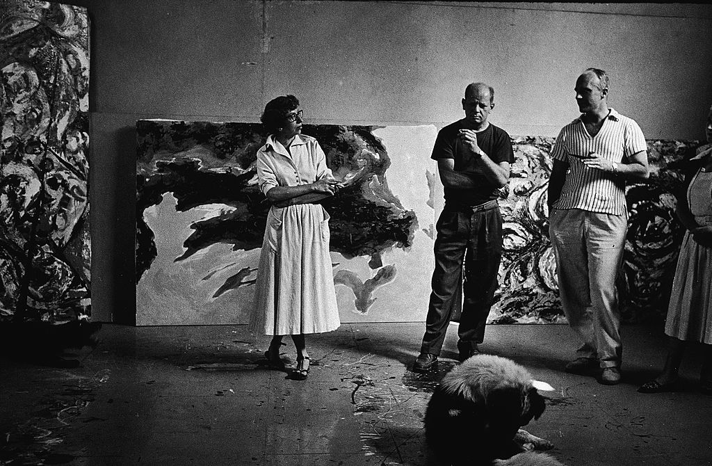 American abstract expressionist painter Jackson Pollock and his wife Lee Krasner and an unidentified couple stand around a dog and smoke in his studio at 'The Springs,' East Hampton, New York